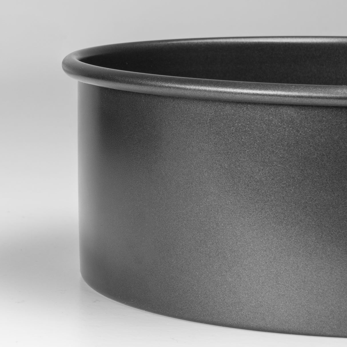 Close-up of a dark grey round cake pan on a light grey background