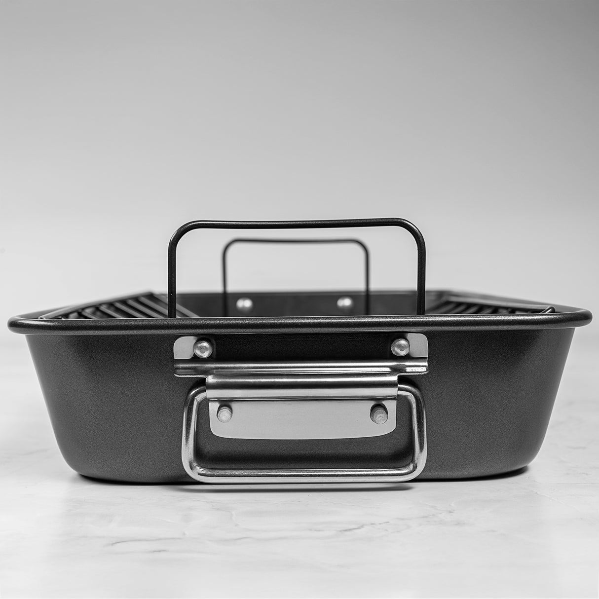 Side profile shot of a black rectangular roasting tin with handle on white background