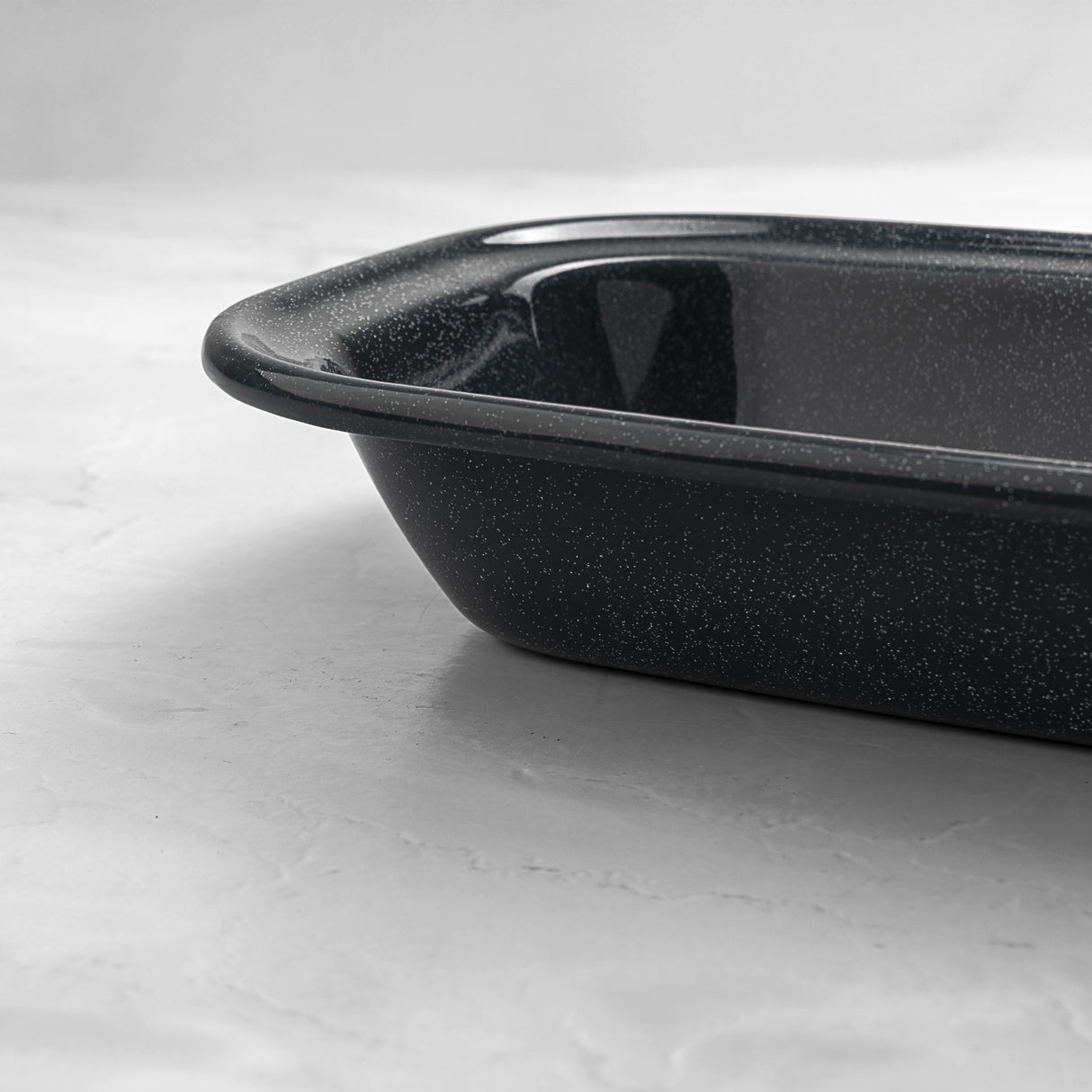 Close-up of a rectangular grey speckled enamel pie dish, showing deep sides and smooth enamel finish for oven baking.