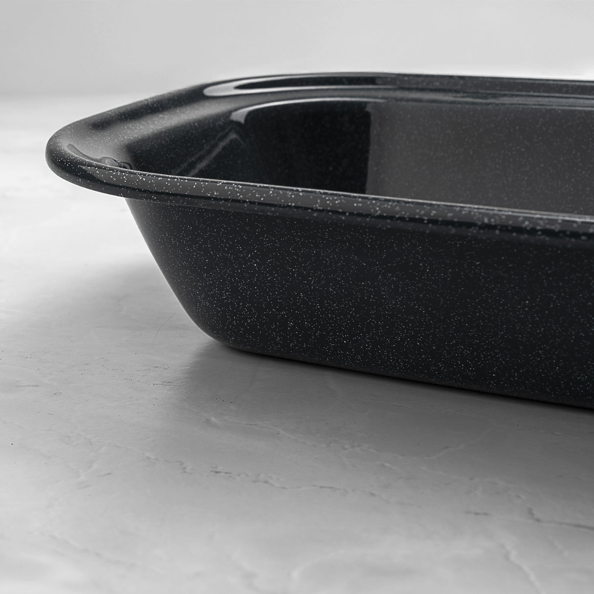 Close-up of a rectangular grey speckled enamel pie dish, showing deep sides and smooth enamel finish for oven baking.