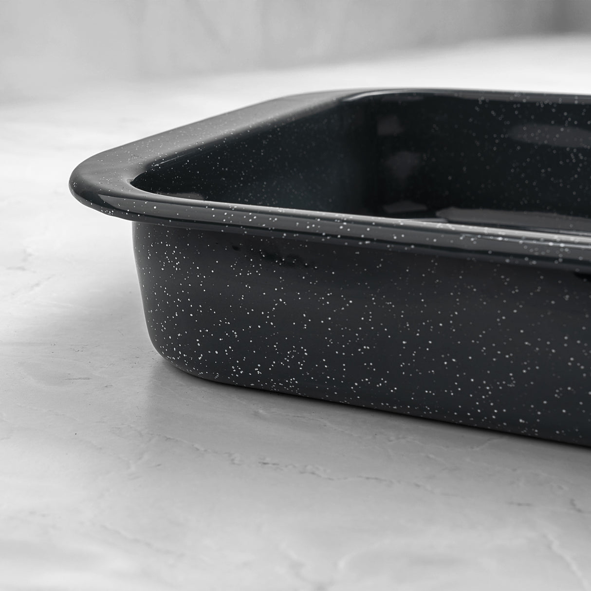 Grey enamel speckled roasting pan on a light grey surface