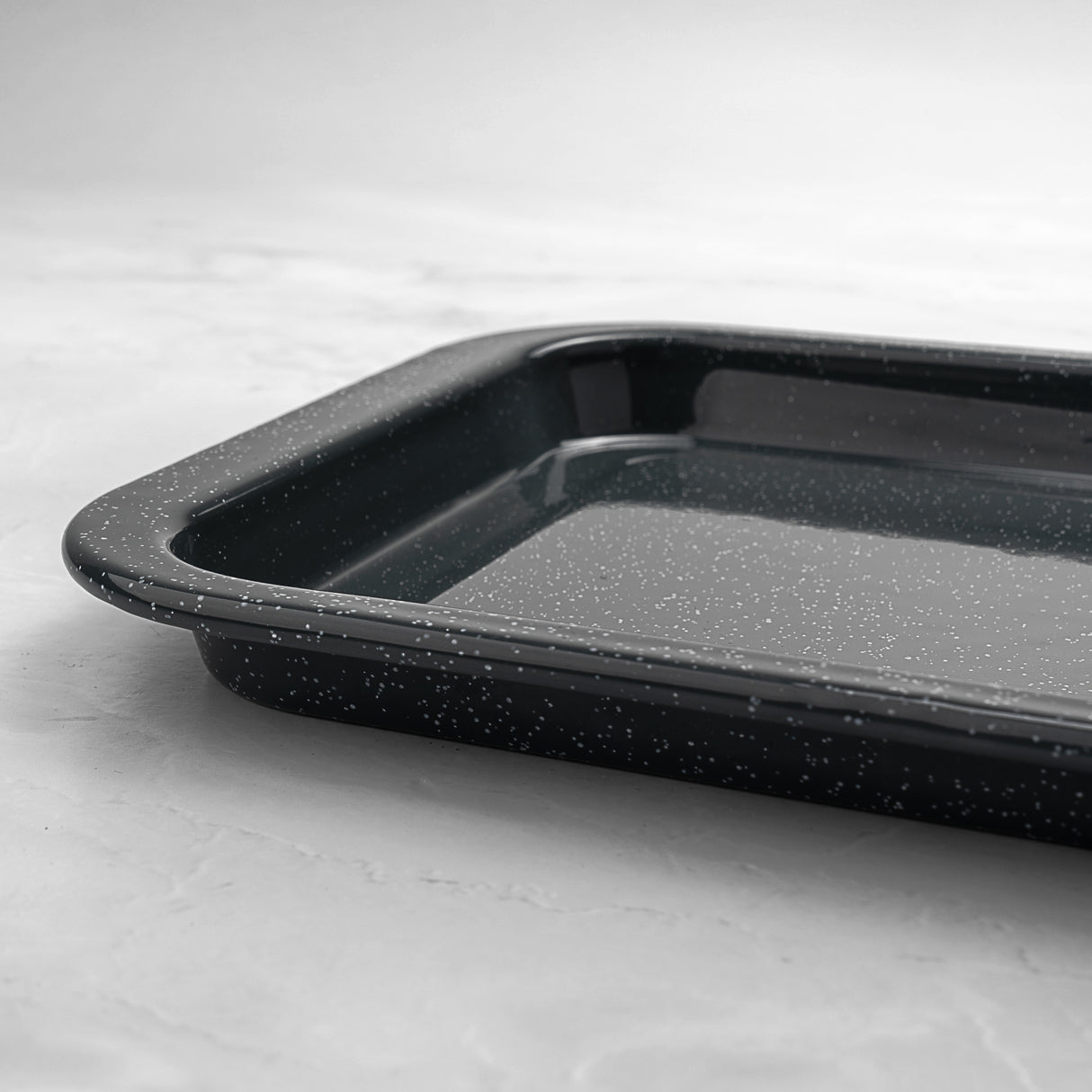 Grey speckled enamel baking tray on a light grey background