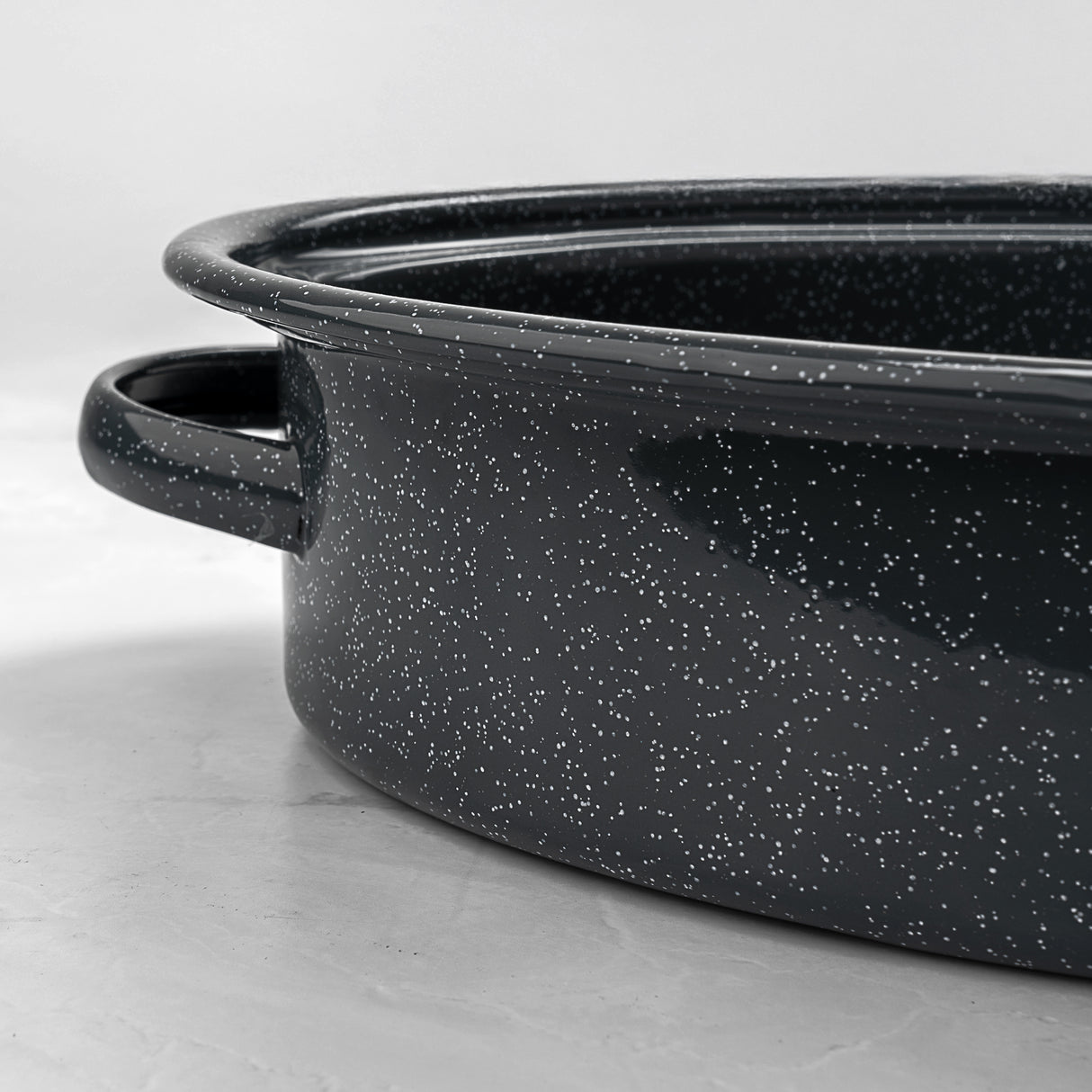 Grey speckled enamelled cast iron casserole pan on a light grey background