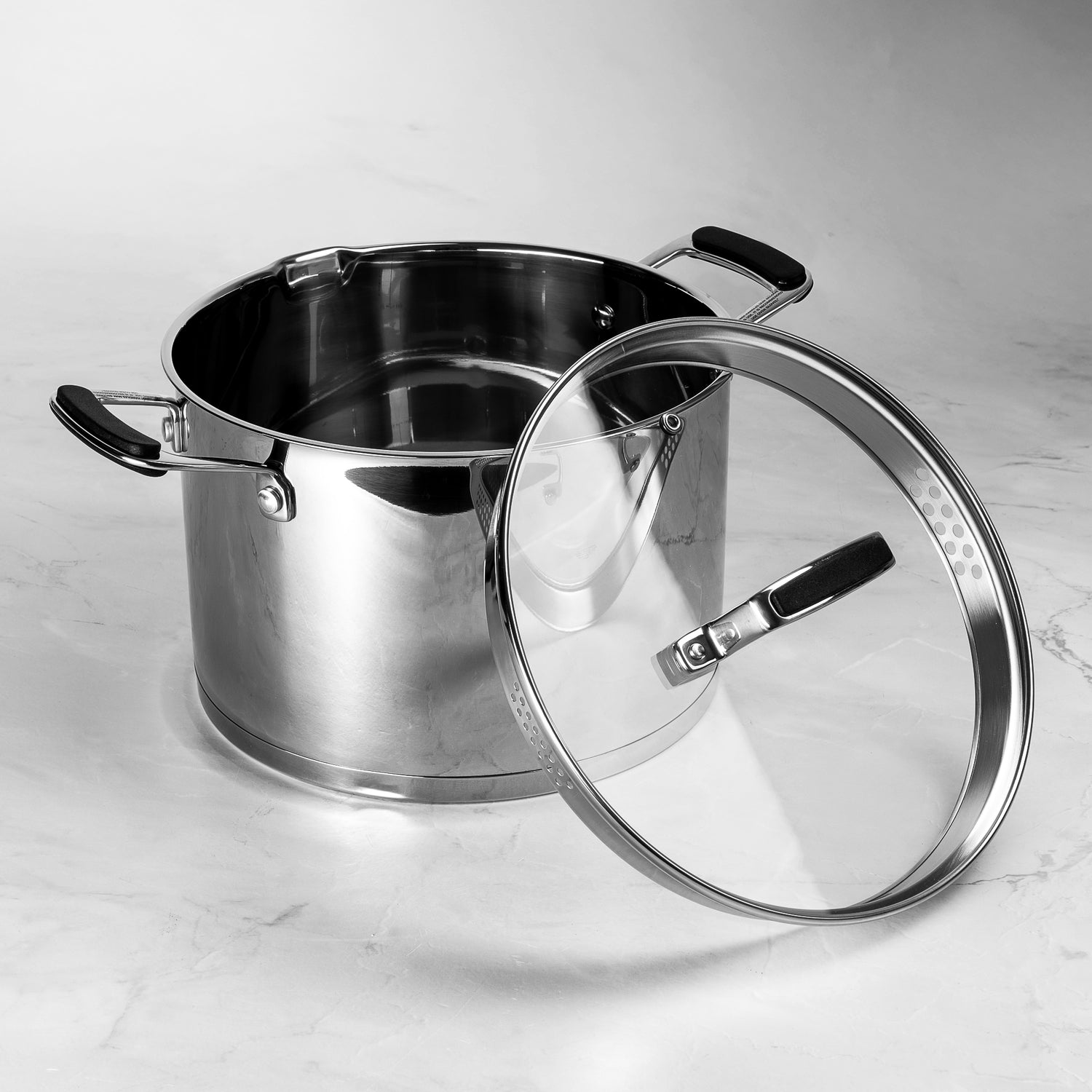 Stainless steel pot with a glass lid on a marble surface
