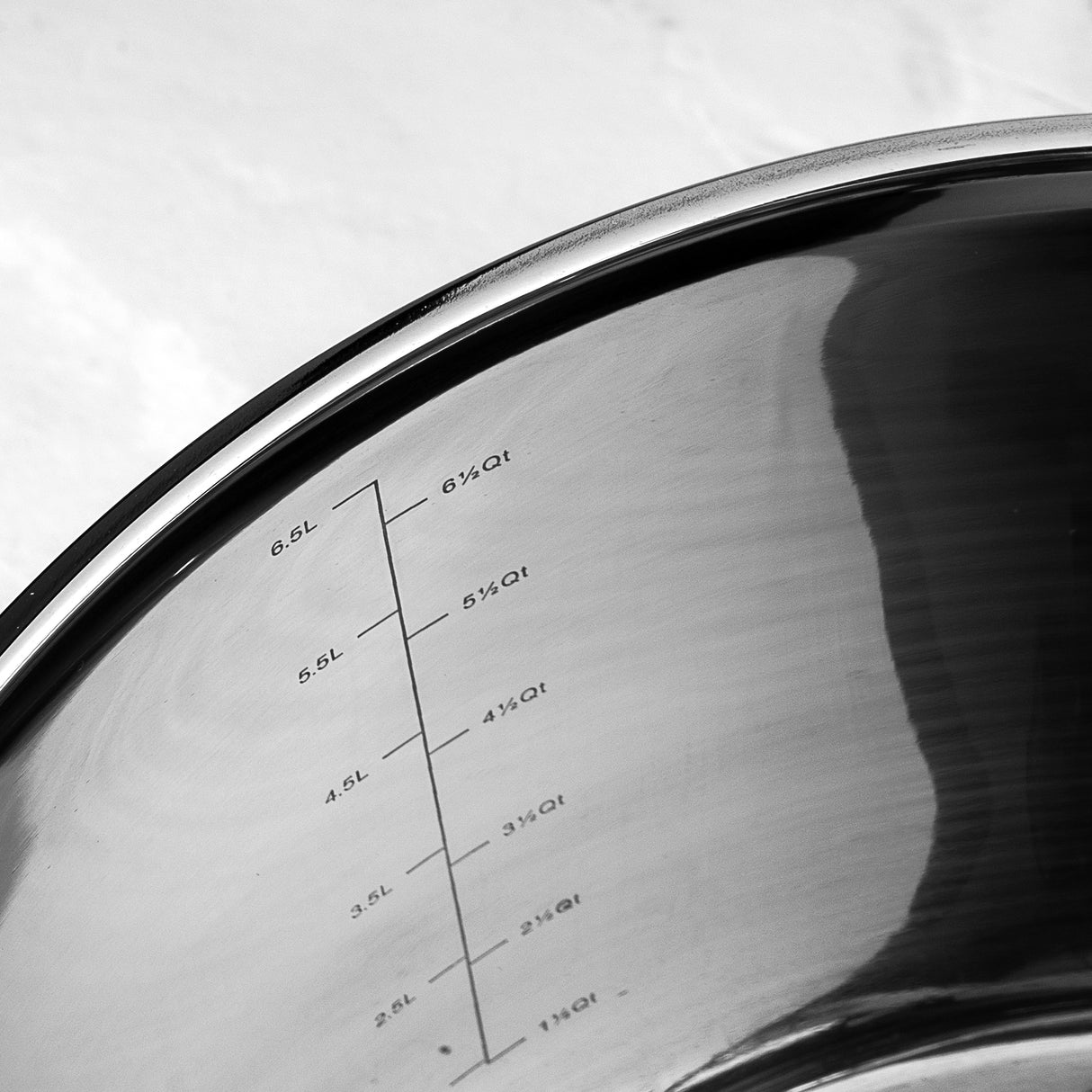 Stainless steel pan with measurements markings on the interior side, on a white background