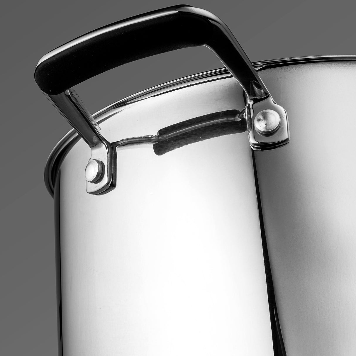Close-up of a stainless steel pot with a black handle on a gray background