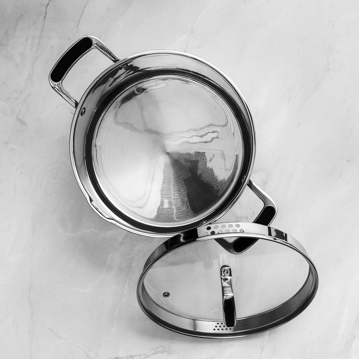 Stainless steel pot with lid on a light gray background