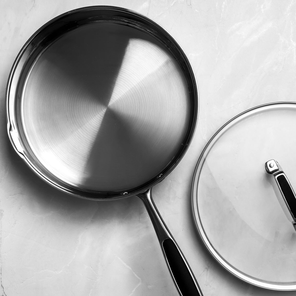 Frying pan with lid on a light gray surface