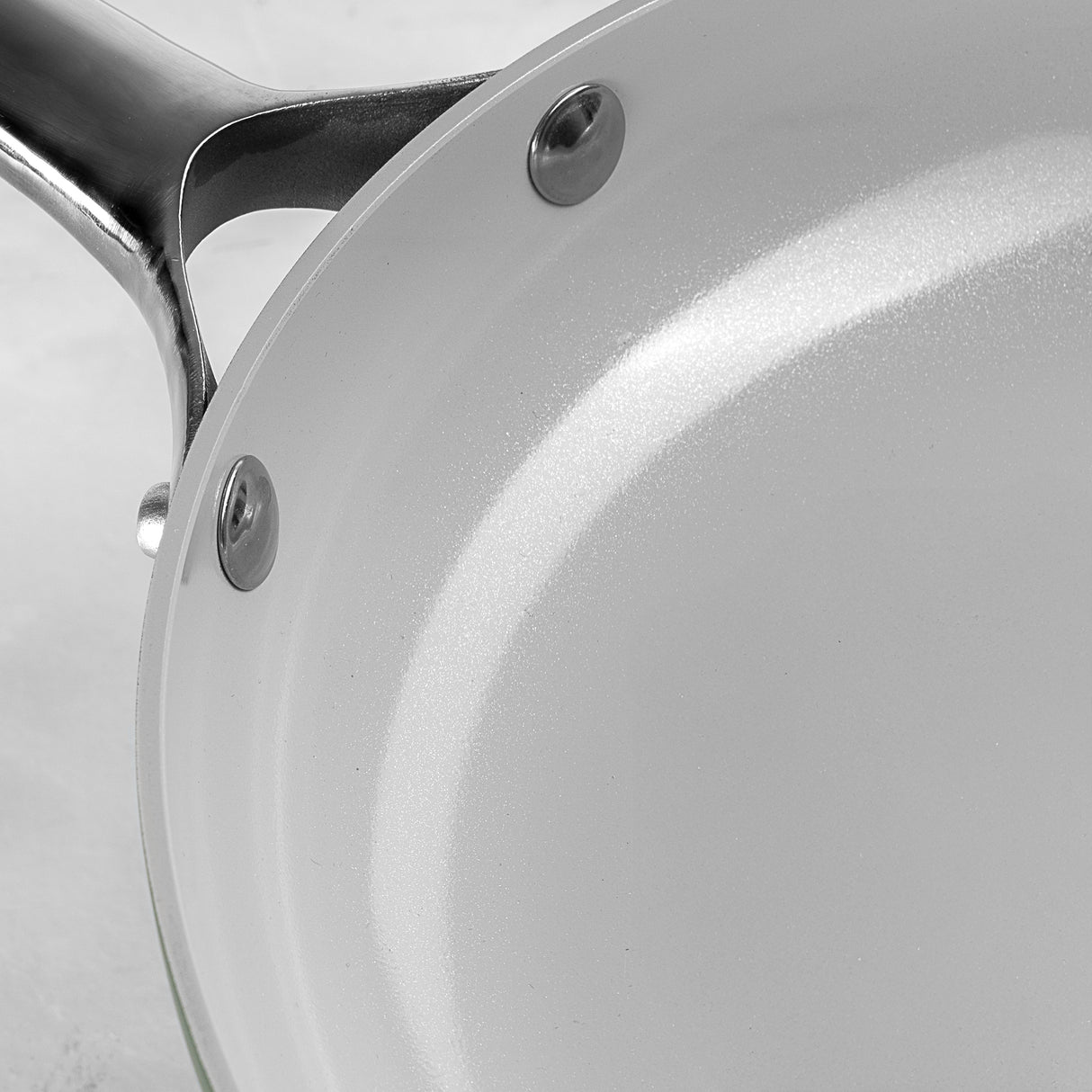 Close-up of a ProChef ceramic-coated aluminium frying pan interior with a white non-stick surface and riveted stainless steel handle.