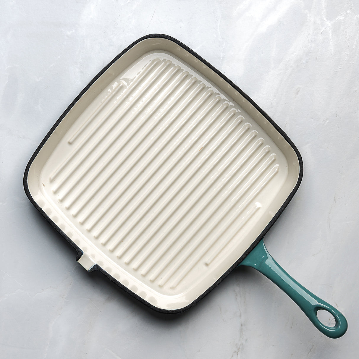Square enamel cookware with a teal handle on a light grey background