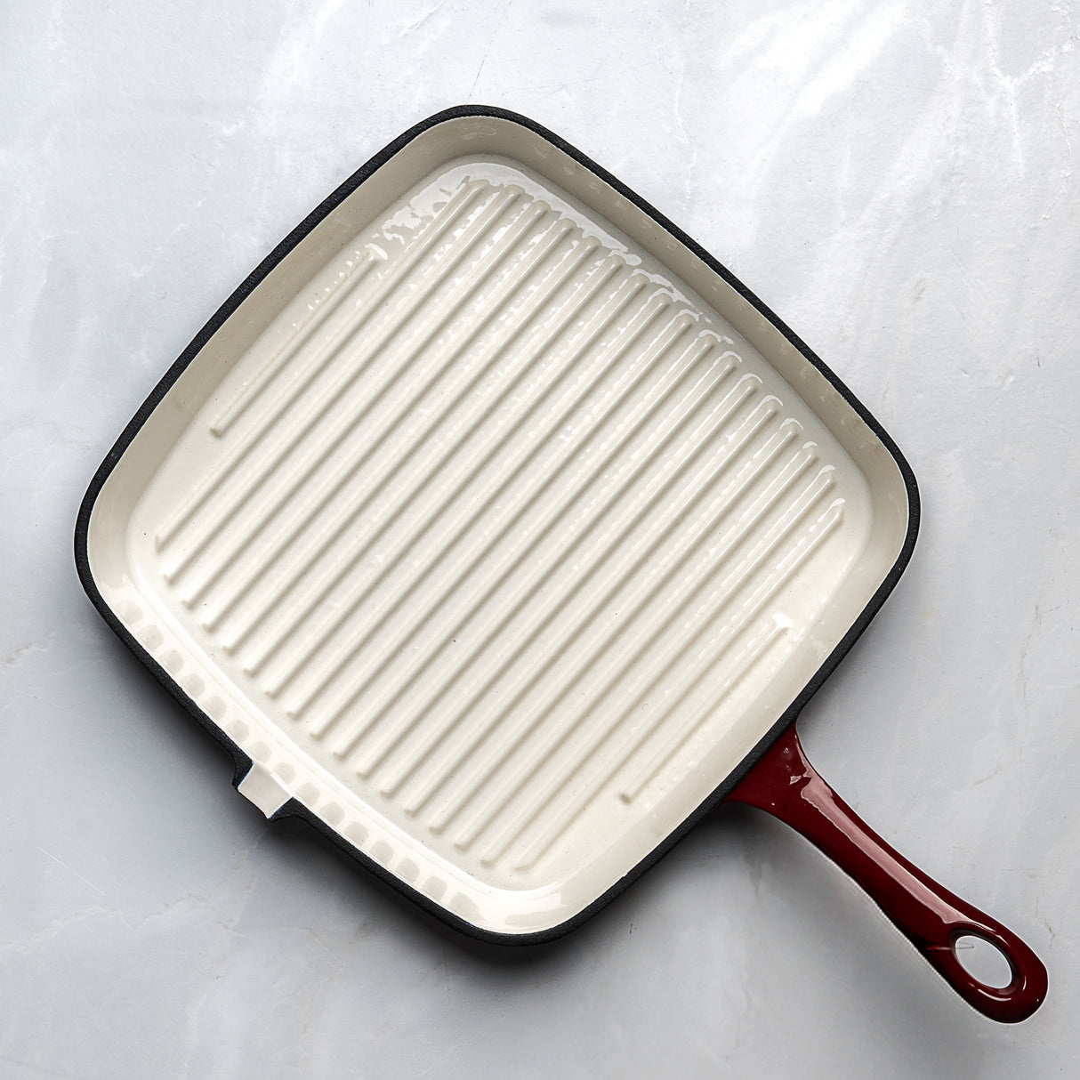 Square grill pan with a red handle on a light gray background