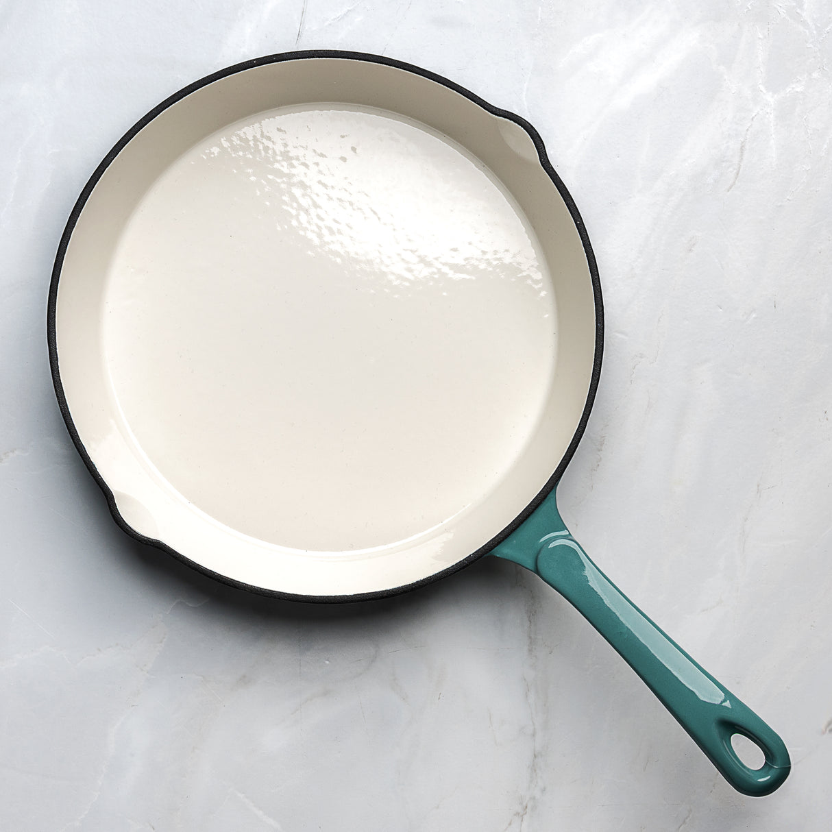 Teal enameled cast iron skillet on a light gray background