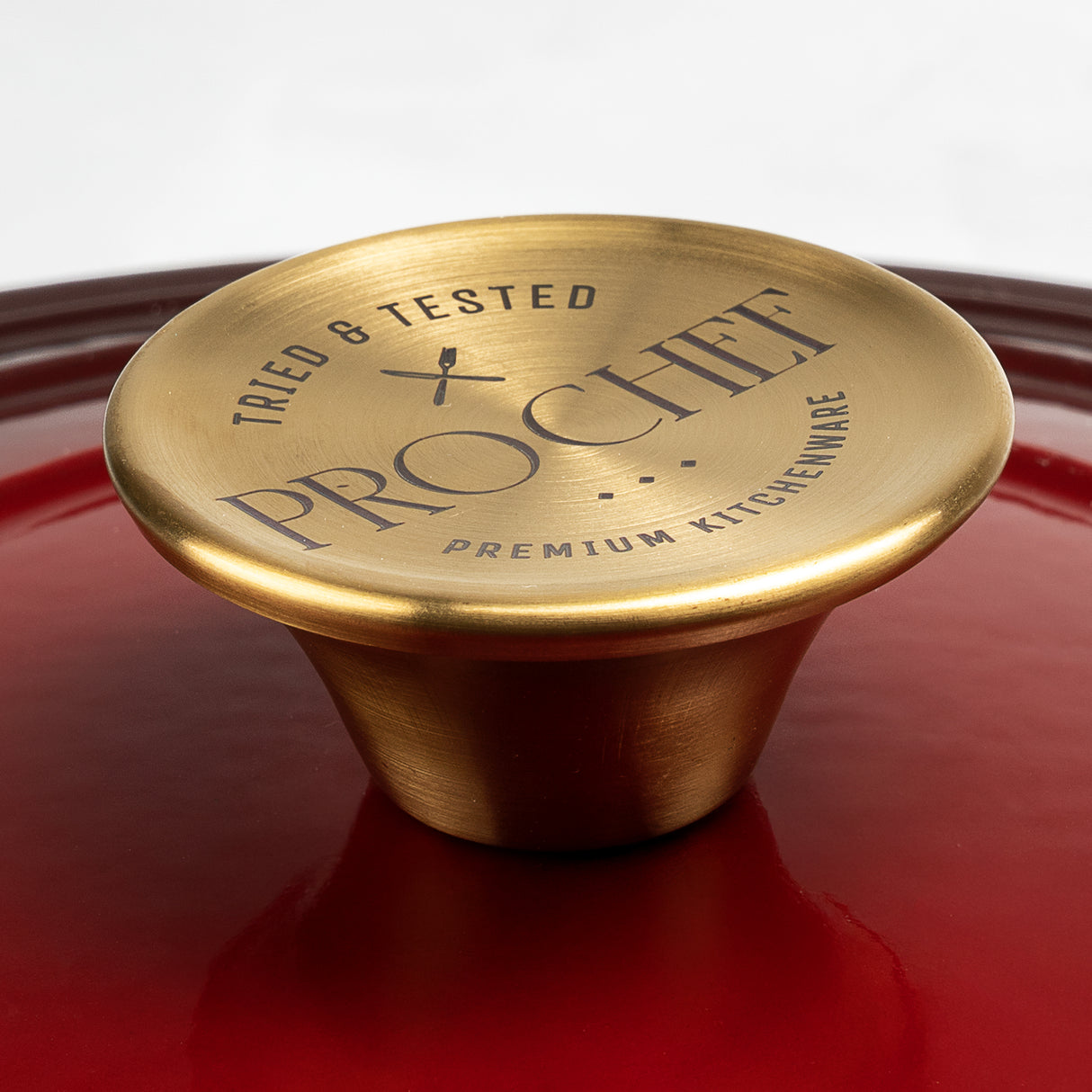 Close-up of ProChef cast iron casserole lid in deep red enamel with a gold metallic knob engraved with the ProChef logo and the words ‘Tried & Tested Premium Kitchenware’.