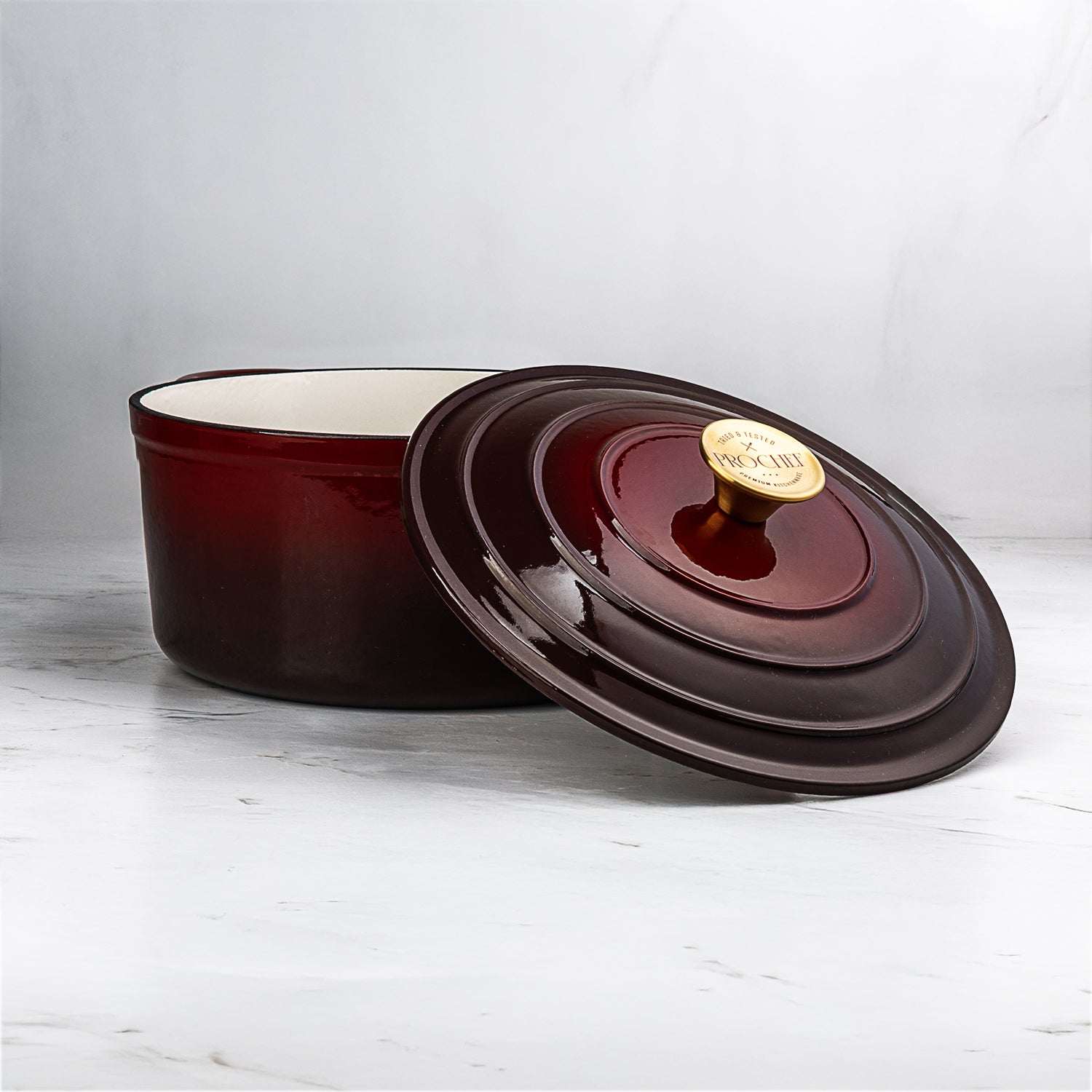 ProChef round cast iron casserole dish in deep red enamel with white interior, shown with matching lid featuring a gold knob engraved with the ProChef logo.