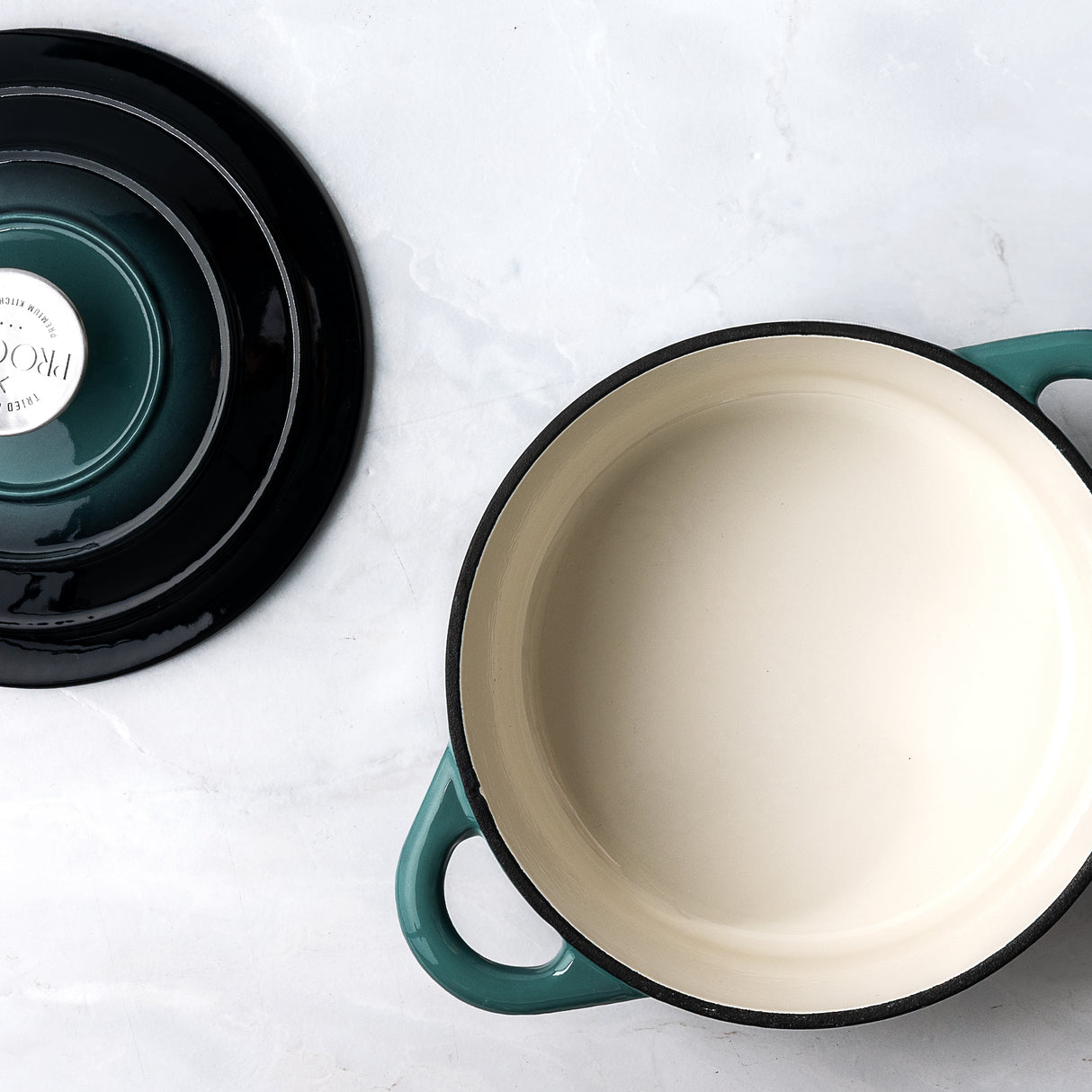 ProChef teal cast iron casserole dish with white enamel interior, shown with its matching lid placed beside it on a light surface.