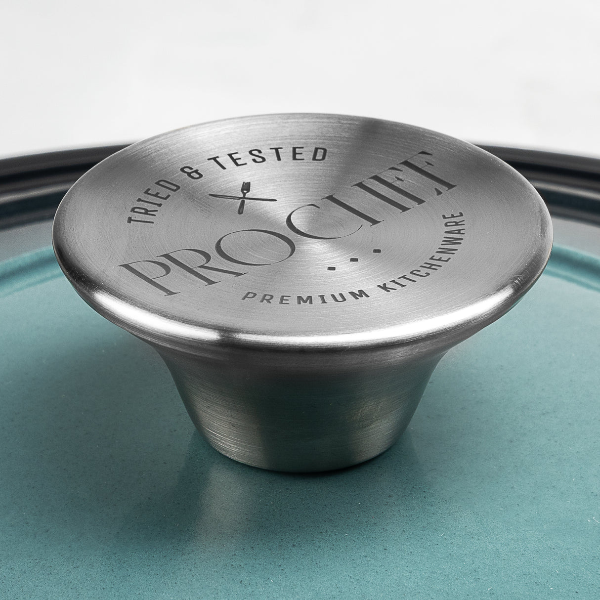 Close-up of ProChef cast iron casserole lid showing brushed stainless steel knob engraved with the ProChef logo and the words ‘Tried & Tested Premium Kitchenware’.