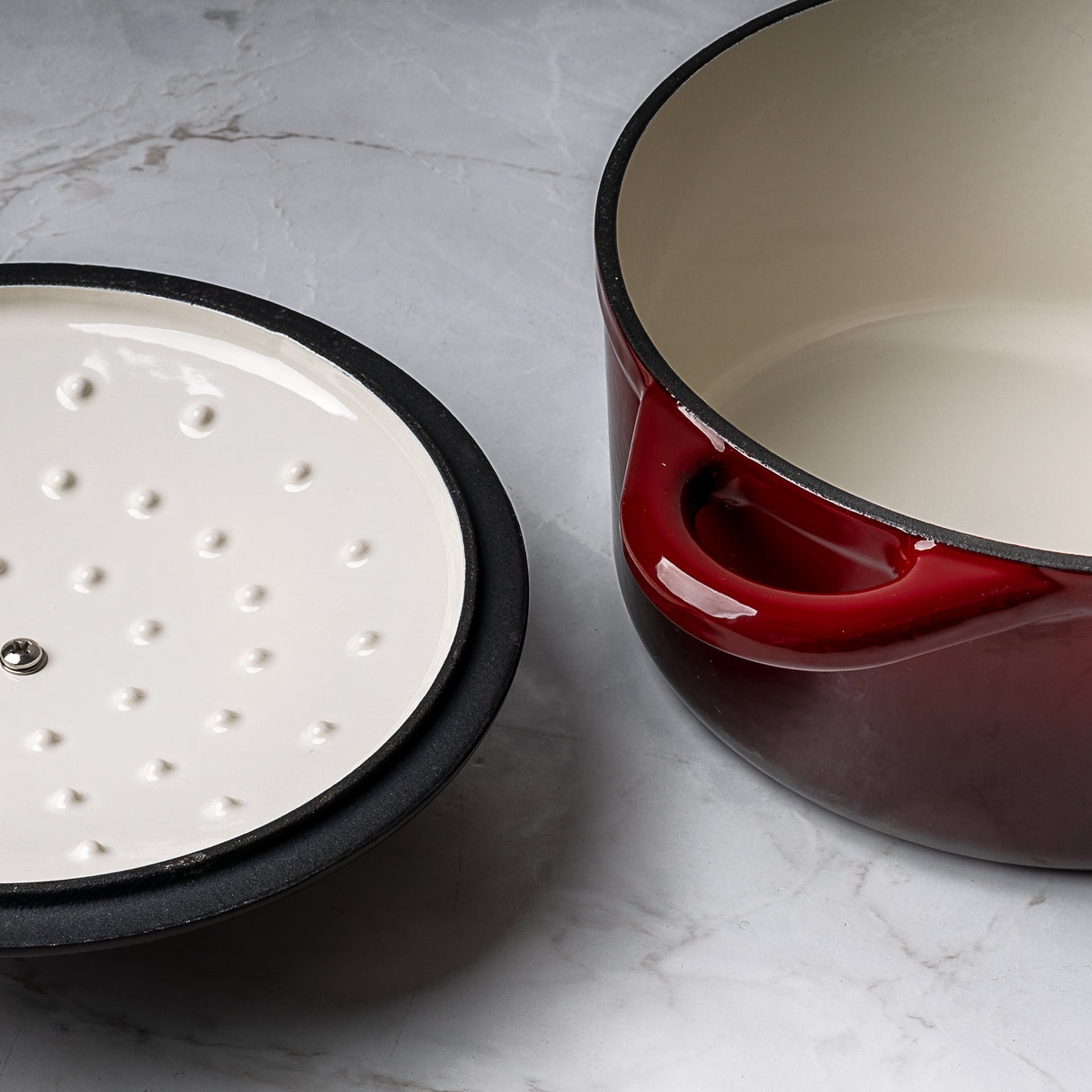 ProChef red cast iron casserole dish with white enamel interior, shown with matching lid featuring condensation spikes on the underside.