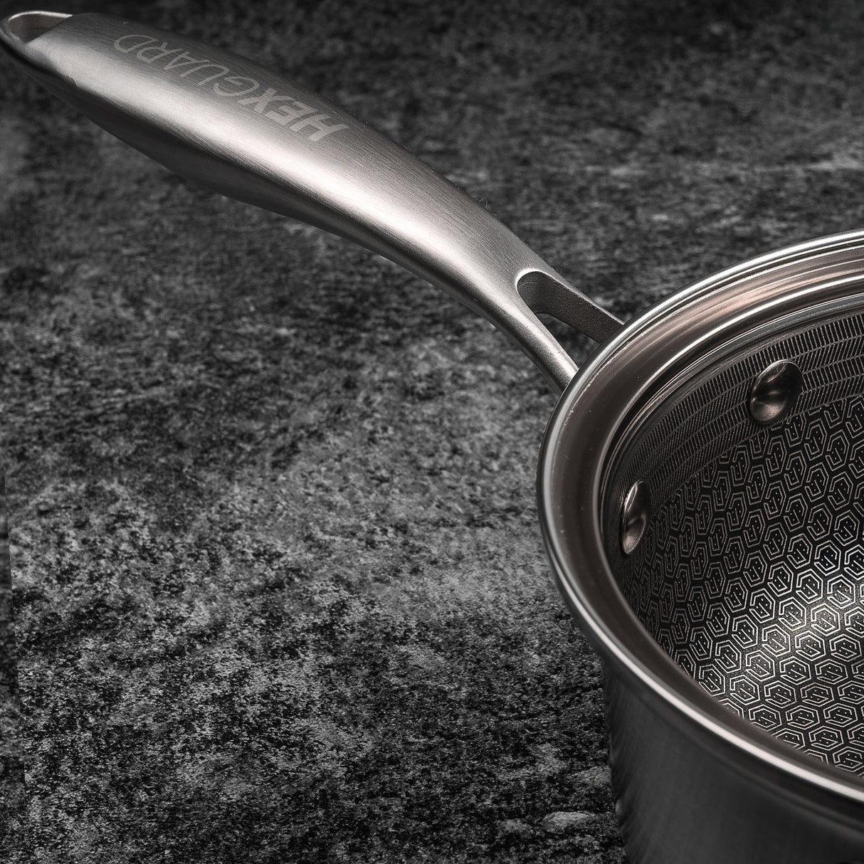 Stainless steel saucepan with handle on a dark textured surface