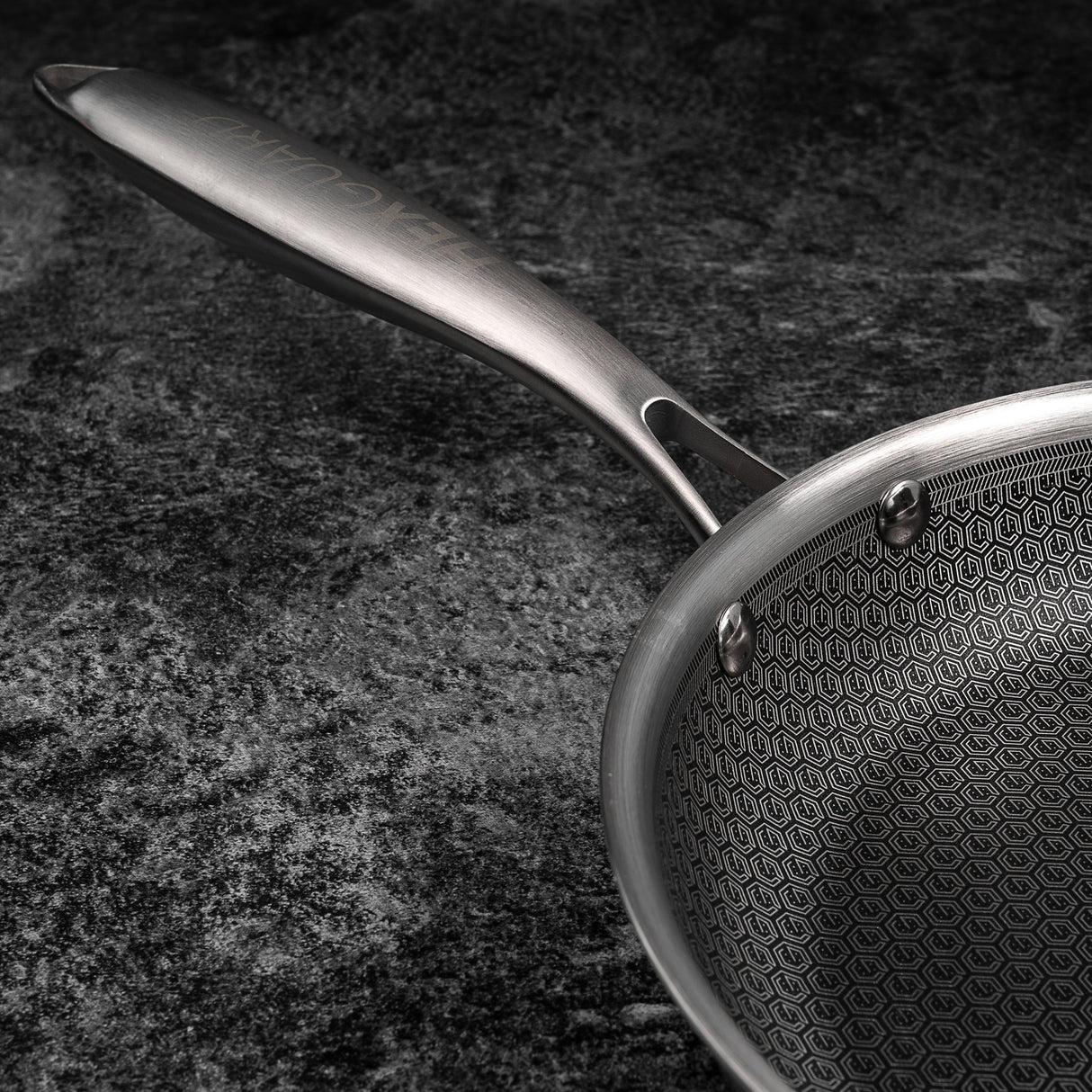 Silver frying pan with a textured surface on a dark background