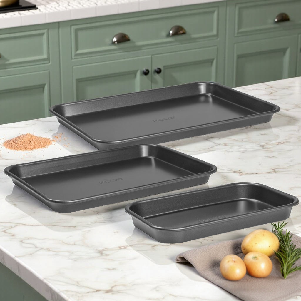 Set of three baking trays on a kitchen counter with green cabinets in the background.