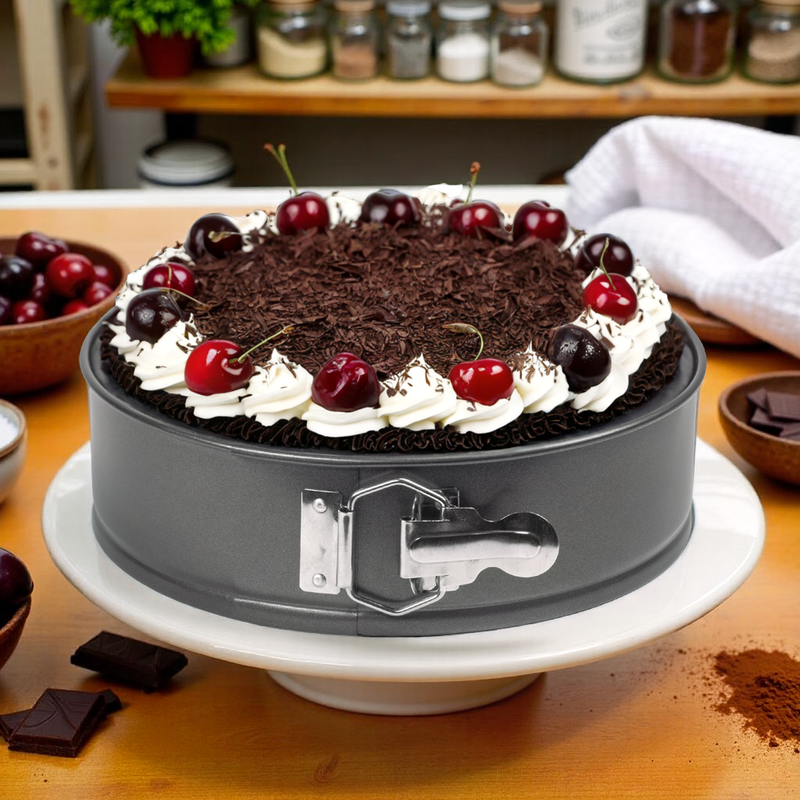 Chocolate cake with cherries on a gray cake stand in a kitchen setting