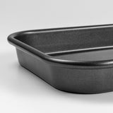 Close up shot of a black carbon steel rectangular baking tray with rounded corners on a light grey background