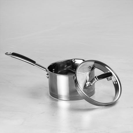 Stainless steel saucepan with lid on a light gray background