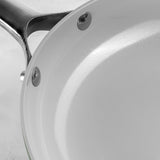 Close-up of a ProChef ceramic-coated aluminium frying pan interior with a white non-stick surface and riveted stainless steel handle.