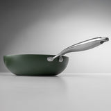 Green frying pan with a silver handle on a gray background