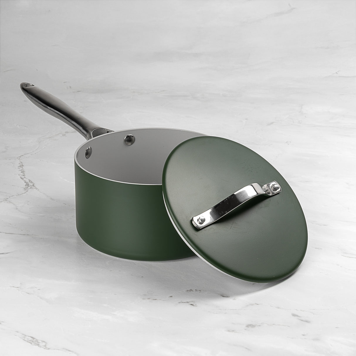 Green saucepan with lid on a white marble surface