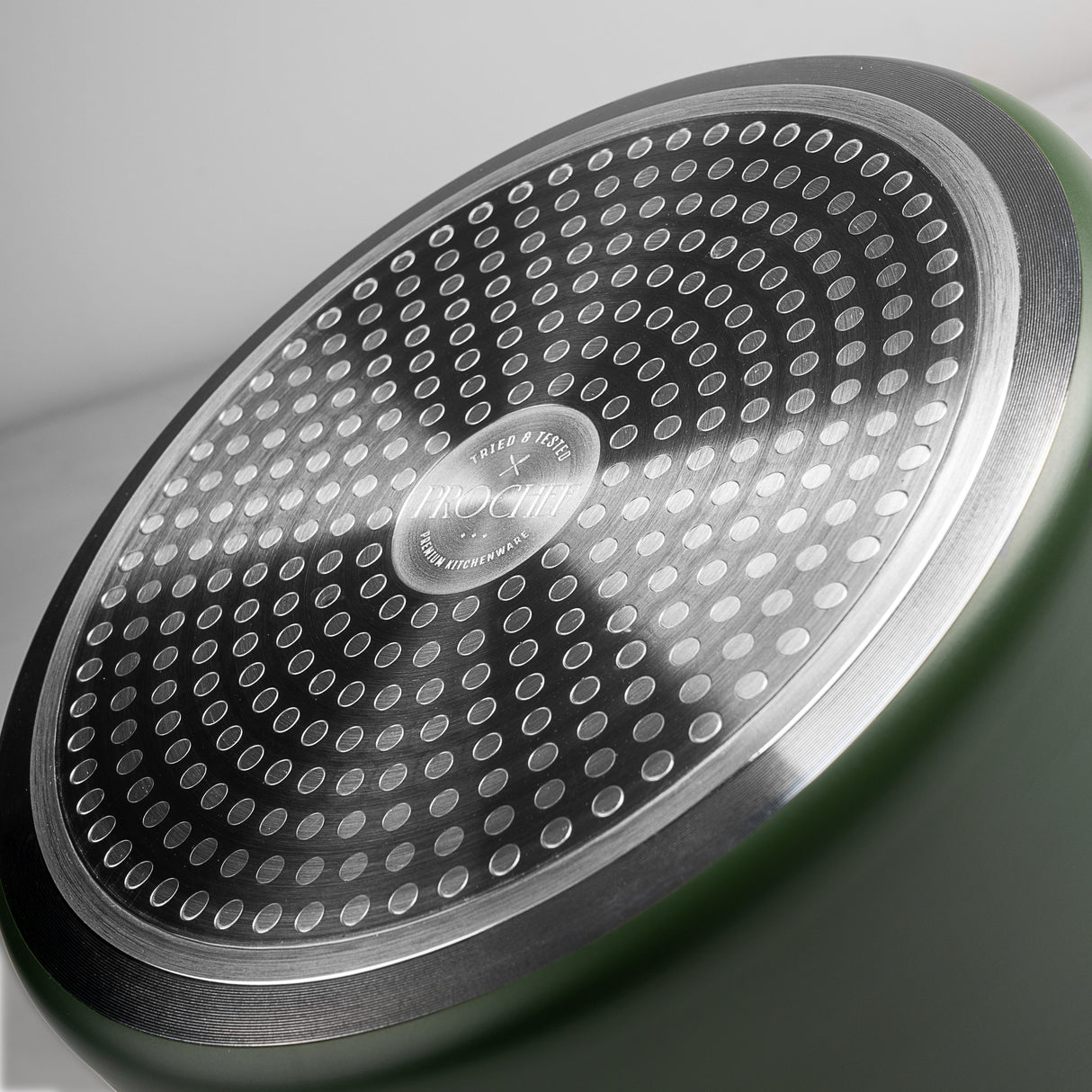 Close-up of ProChef frying pan base with stainless steel induction plate featuring circular dot pattern for even heat distribution.