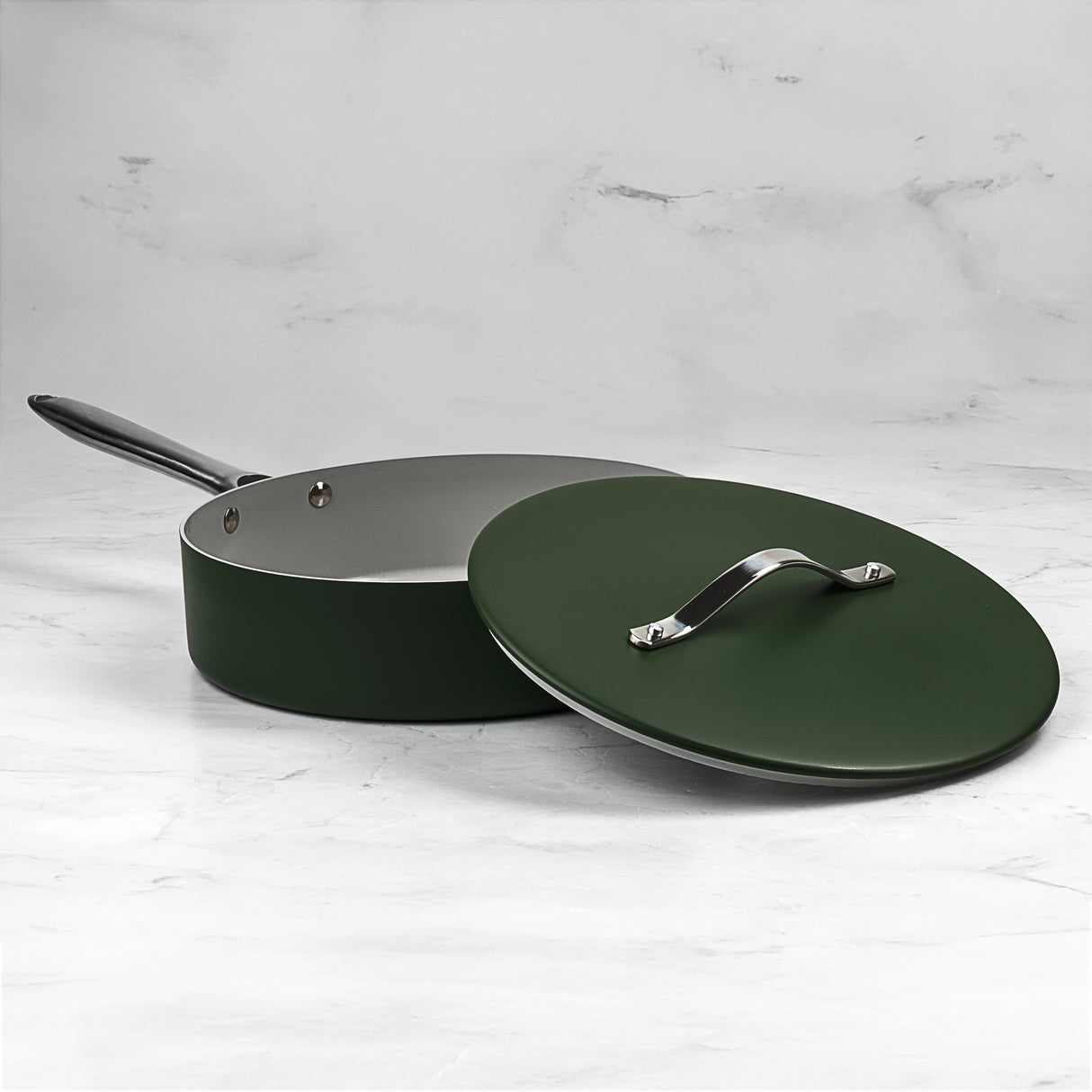 Green frying pan with lid on a light gray background
