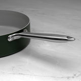 Green saute pan with a silver handle on a marble surface