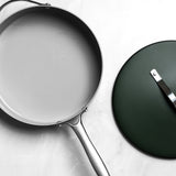 Frying pan with a lid on a light gray background