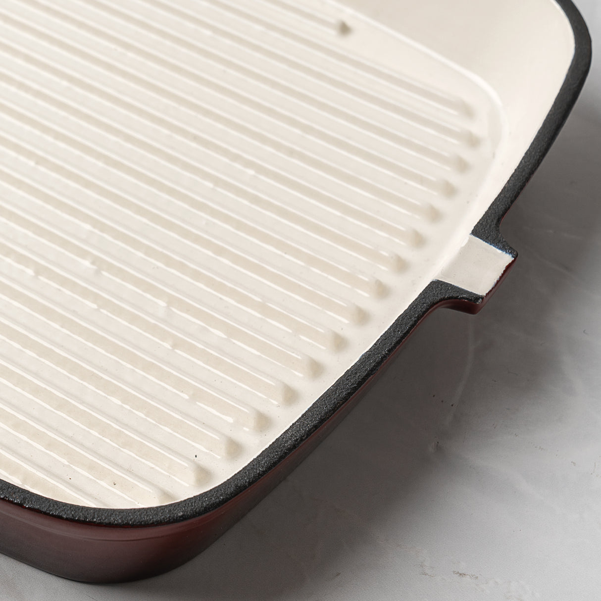 Close-up of a grill pan with a ribbed surface on a light gray background