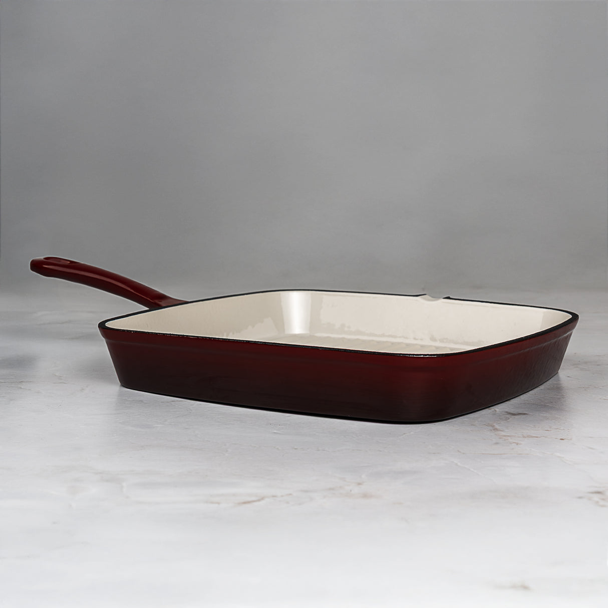 Square enameled cast iron skillet with red-brown exterior and white interior on a light gray background