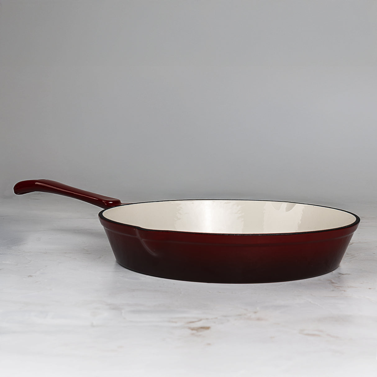 Red cast iron frying pan on a light gray background