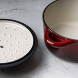 ProChef red cast iron casserole dish with matching lid, shown open to display white enamel interior and self-basting lid underside with raised condensation dots, set on a grey marble surface.