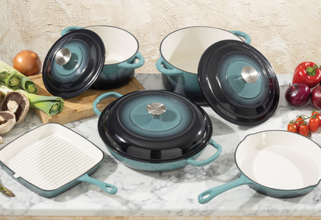 Set of ProChef cast iron cookware with lids and handles on a marble surface with vegetables.