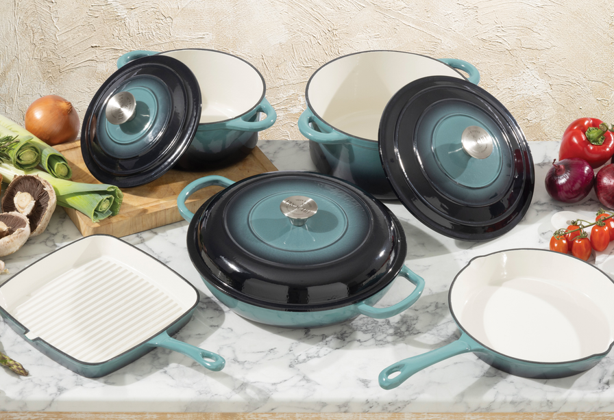 Set of ProChef cast iron cookware with lids and handles on a marble surface with vegetables.