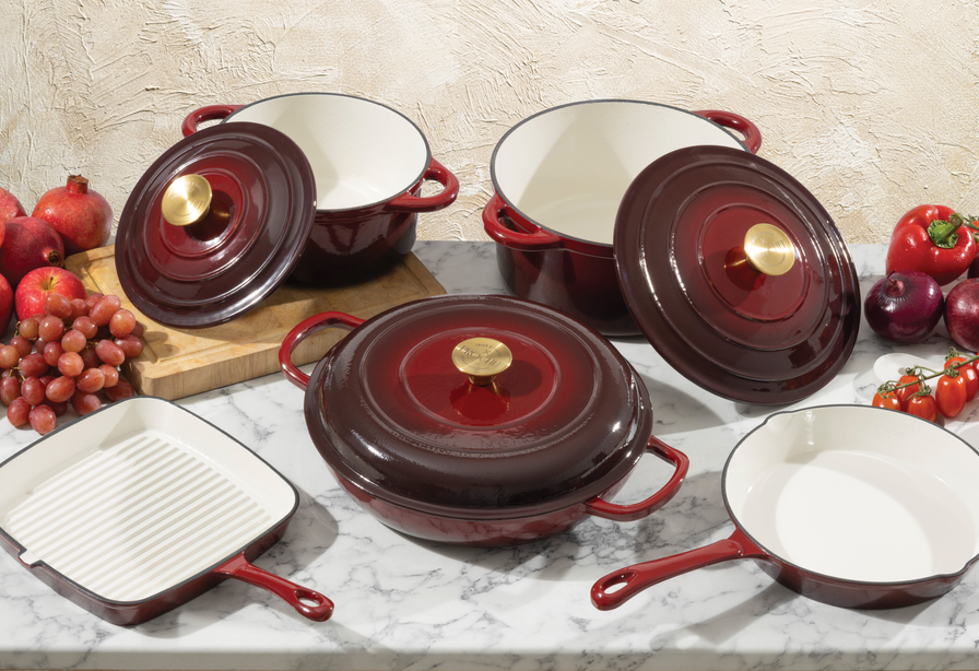 Set of ProChef deep red enamelled cast iron cookware with white interiors on a marble surface.
