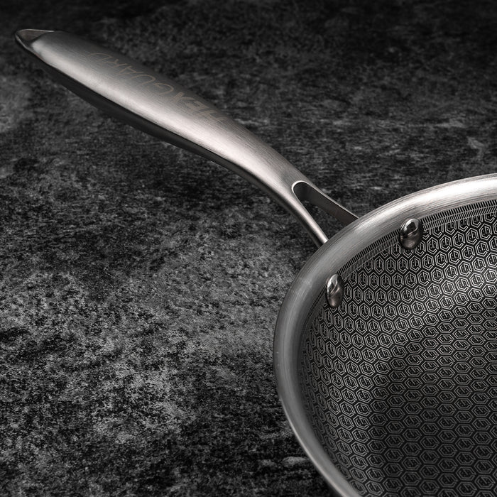 Silver frying pan with a textured surface on a dark background