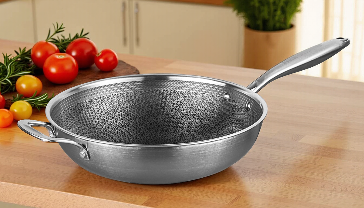 Stainless steel wok on a wooden surface with vegetables in the background