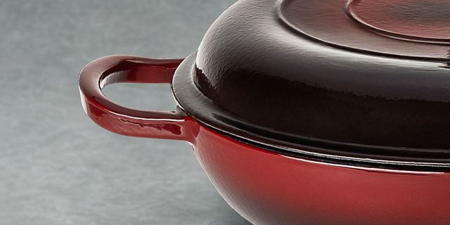 Red cast iron ProChef cookware with a lid on a grey background