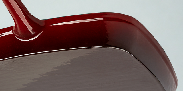 Close-up of the underside of a red ProChef cast iron grill pan showing smooth enamel base and handle.
