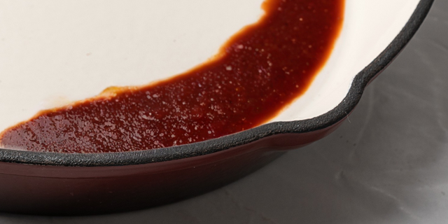 Red sauce in a ProChef deep garnet cast iron skillet on a grey background