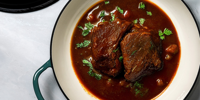 ProChef teal cast iron casserole dish filled with braised beef in rich sauce, garnished with fresh herbs.