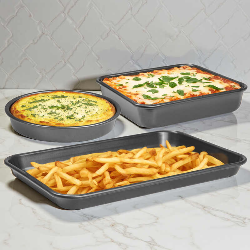 Three baking trays with different dishes on a marble countertop.
