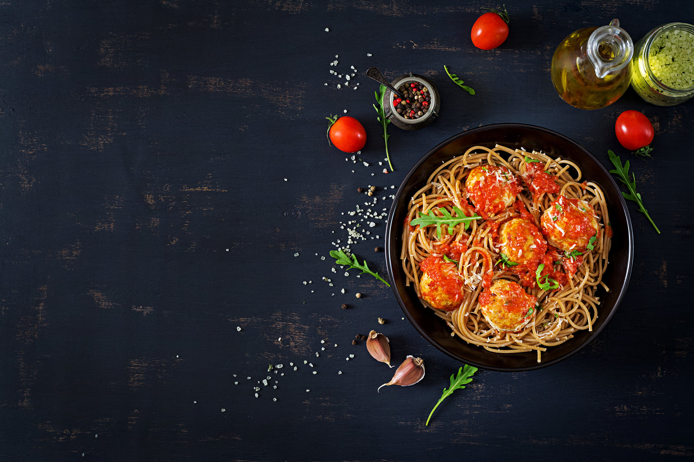 Spaghetti dish with tomato sauce and meatballs on a dark surface