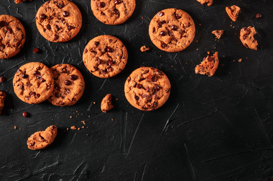 Chocolate chip cookies scattered on a dark surface